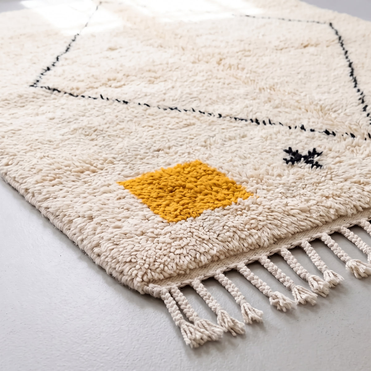 Fringe and corner detail of Azilal rug showing gold patch and knotted tassel edge