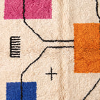 Texture detail of Azilal rug showing magenta and orange patches with black connecting line and plus-sign motif
