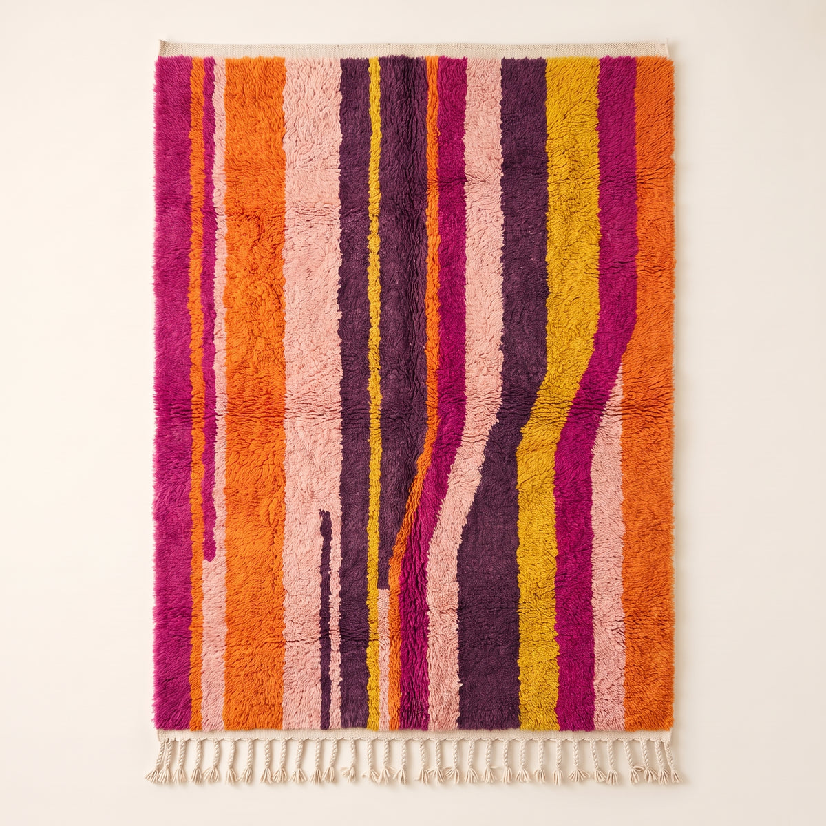 Tanina Azilal rug in magenta, orange, purple, pink and yellow vertical stripes on plain background
