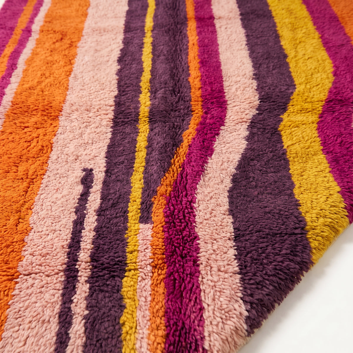 Close-up of Tanina rug pile showing vertical stripes in magenta, orange, purple and pink