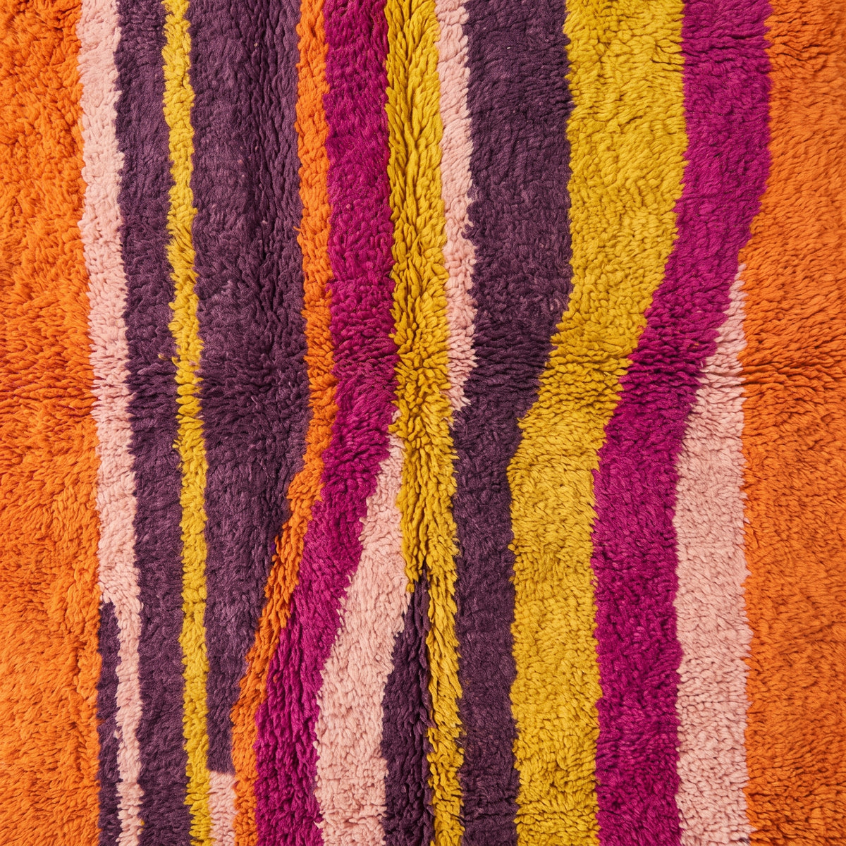 Close-up of hand-knotted vertical stripes showing yellow, magenta and purple wool tones