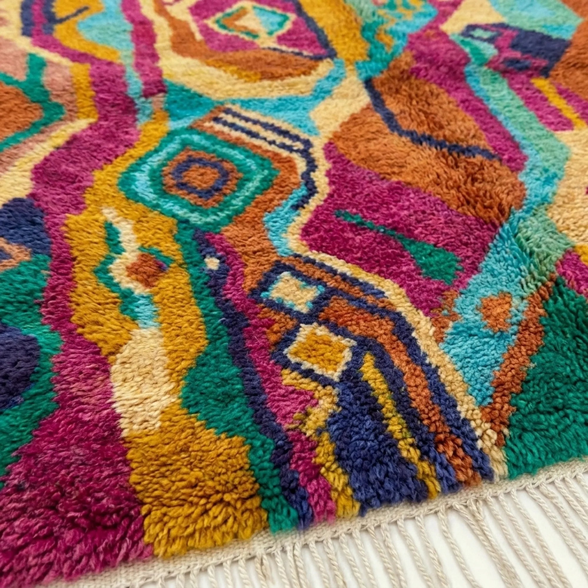 Fringe and lower-edge detail of Awrmas beside flowing magenta, orange, teal and cream motifs