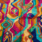 Close-up of Awrmas showing nested diamonds and flowing symbolic lines in saturated multicolor wool