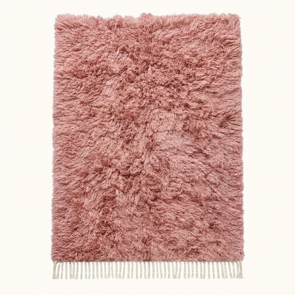 Flat lay of mauve Beni Ourain rug with dense pile and ivory fringe on plain background