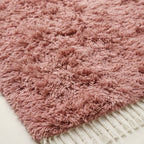 Side angle showing depth of mauve hand-knotted pile and ivory fringe
