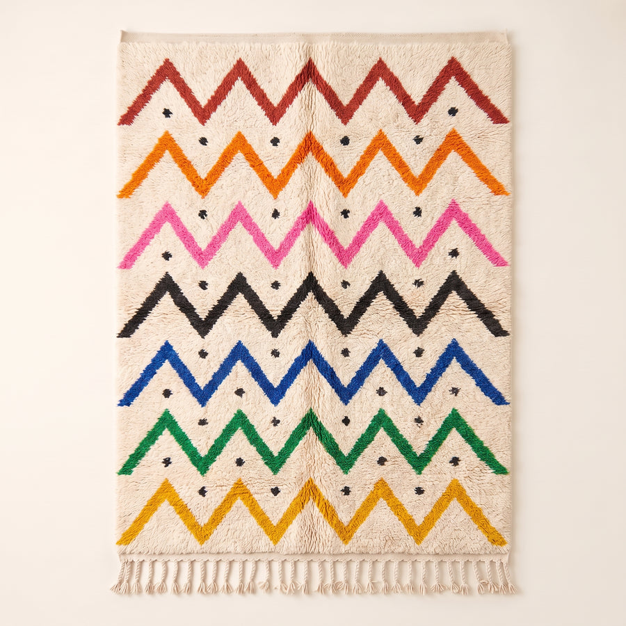 Multicolor Azilal rug with bright zigzag chevron stripes in red, orange, magenta, black, blue, green and gold on an ivory ground, with small black cross accents throughout