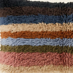 Side view of the Tiwizi Moroccan pillow showing its multicolor striped wool pile