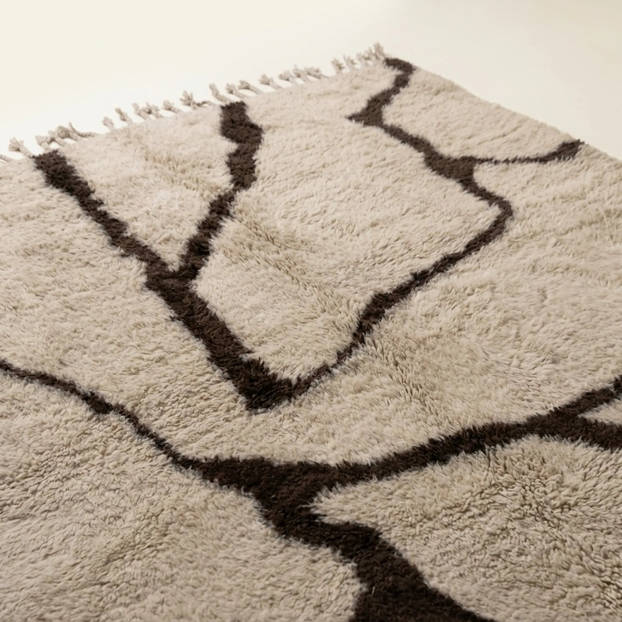 Angled view of the Aylal mushroom and dark brown Beni Ourain rug showing the branch line design.