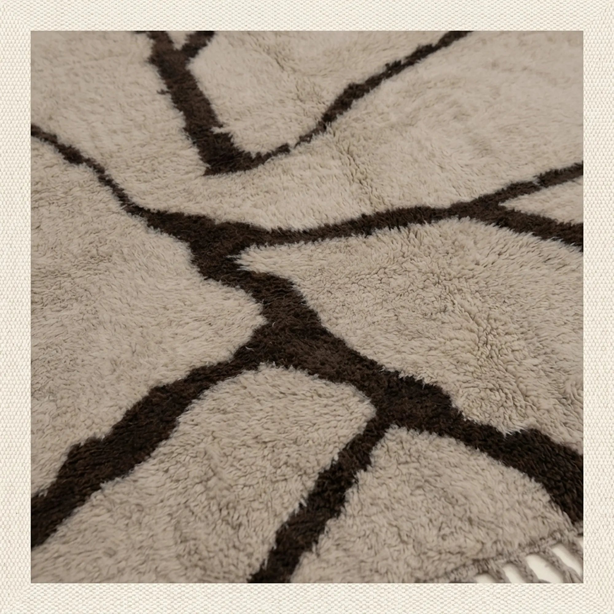 Close-up of the natural Atlas wool pile on the Aylal mushroom and dark brown Beni Ourain rug.