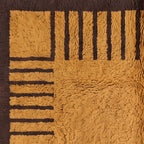 Corner detail of mustard and chocolate Mrirt rug showing border frame and stripe column definition