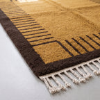 Angled pile detail of mustard striped columns and chocolate border on Mrirt rug showing plush depth