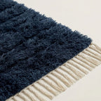 Angled detail of navy Tamazirt rug pile meeting ivory twisted fringe