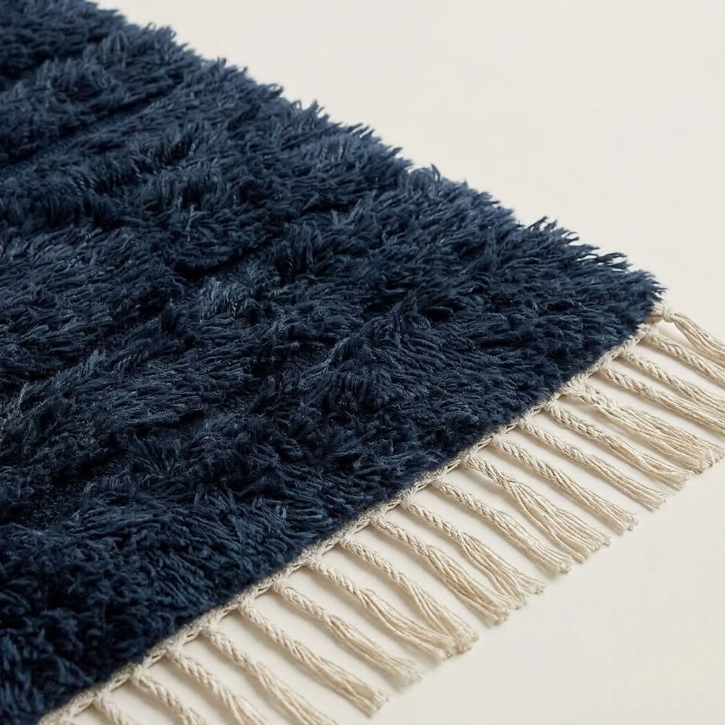 Angled detail of navy Tamazirt rug pile meeting ivory twisted fringe