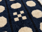 Close-up of navy and cream pebble motif showing hand-knotted wool pile and texture detail