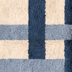Macro detail of cross grid pattern showing color blocks and hand-knotted texture in navy, slate and cream