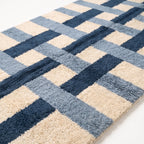 Close-up of navy, slate blue and ivory cross grid pattern showing thick hand-knotted wool pile texture