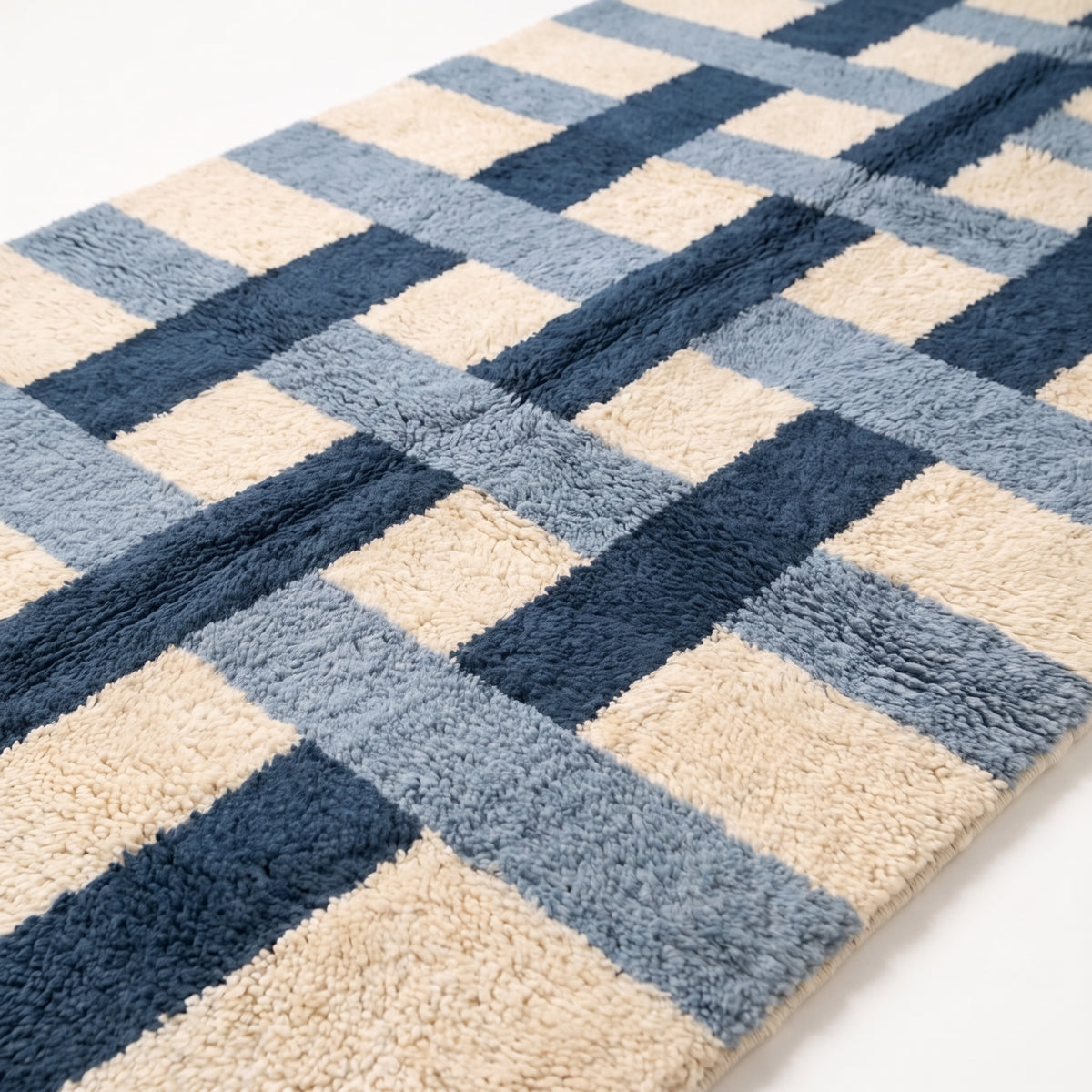 Close-up of navy, slate blue and ivory cross grid pattern showing thick hand-knotted wool pile texture