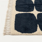 Close-up of the navy rounded grid pattern on the Tamazirt ivory wool rug.