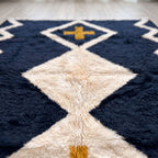 Close-up of gold cross motif and ivory diamond shape on navy ground