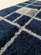 Angled pile detail showing grid lines where navy and ivory blocks meet in hand-knotted weave