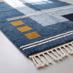 Corner detail showing navy wool, gold square block, ivory stripe border and hand-knotted fringe