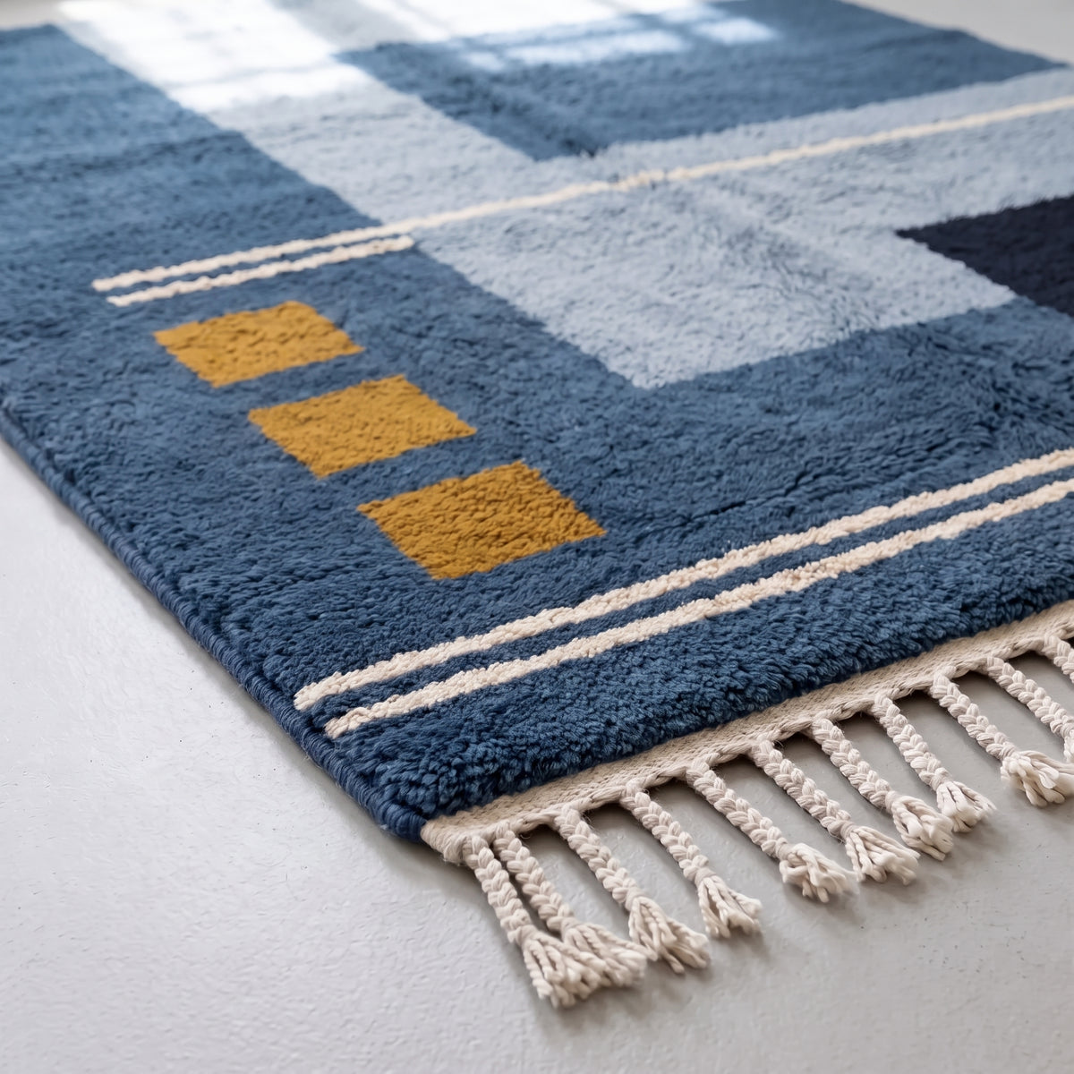 Corner detail showing navy wool, gold square block, ivory stripe border and hand-knotted fringe