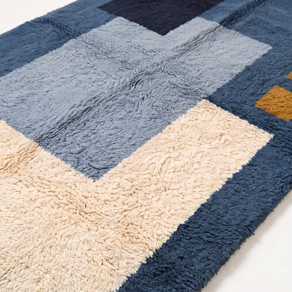 Close-up of navy, slate blue, cream and ivory wool pile showing texture and layered rectangles