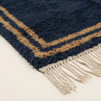 Corner and hand-tied fringe detail of the Isli navy, ochre, and ivory rug.