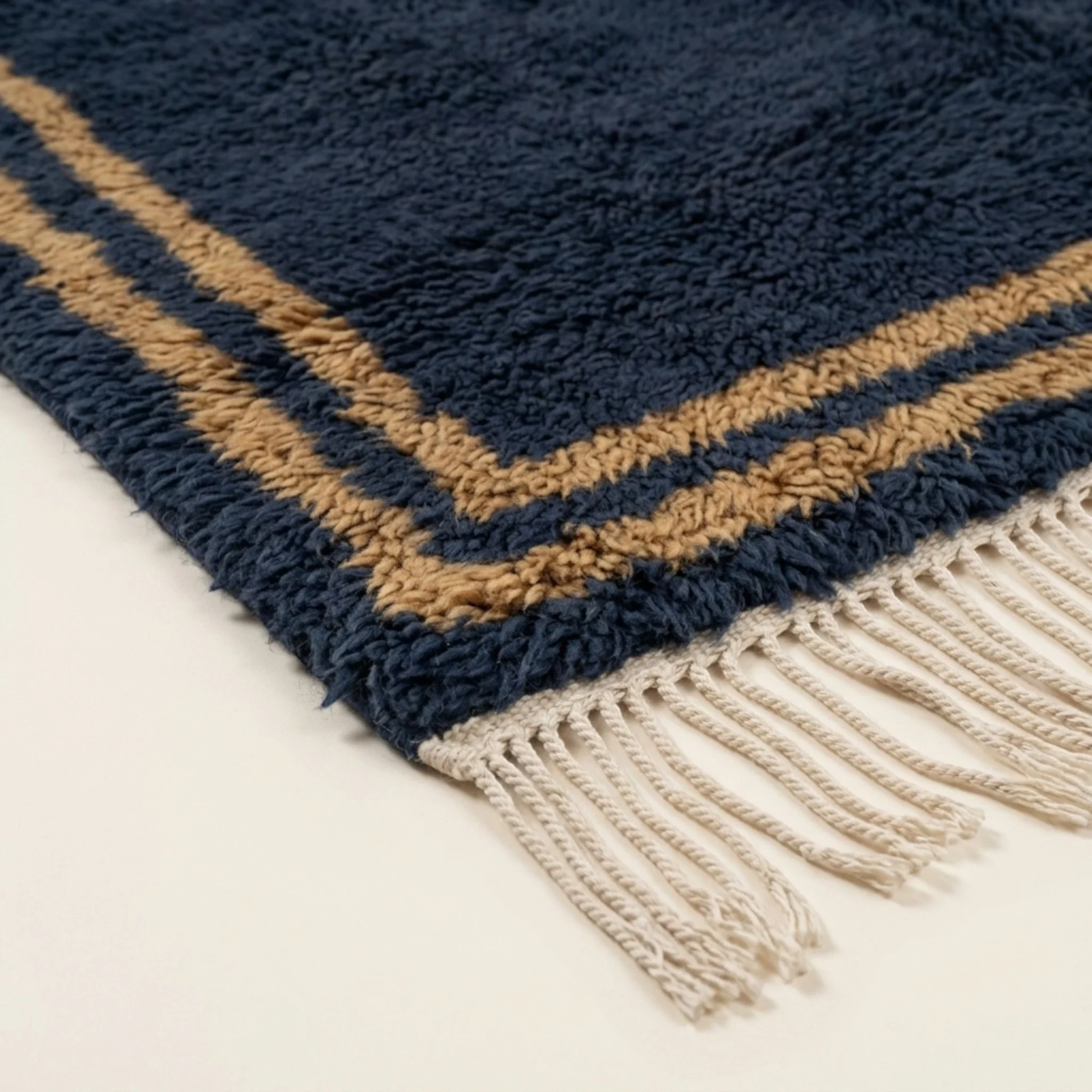 Corner and hand-tied fringe detail of the Isli navy, ochre, and ivory rug.