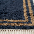Close-up of the ochre and ivory border texture on the Isli navy wool rug.