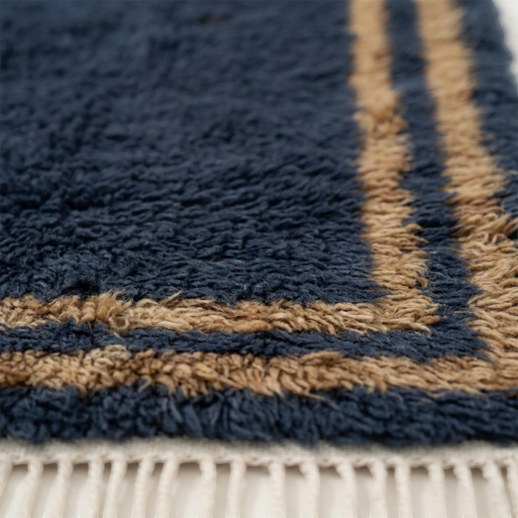 Close-up of the ochre and ivory border texture on the Isli navy wool rug.
