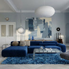 Navy and pale blue Beni Ourain rug Itri in modern living room with curved sofa and glass coffee table