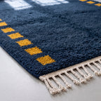Corner detail showing ivory cotton fringe and saffron square column border on navy field
