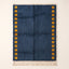 Navy Mrirt rug with saffron-yellow square columns on both sides, flat lay on cream background