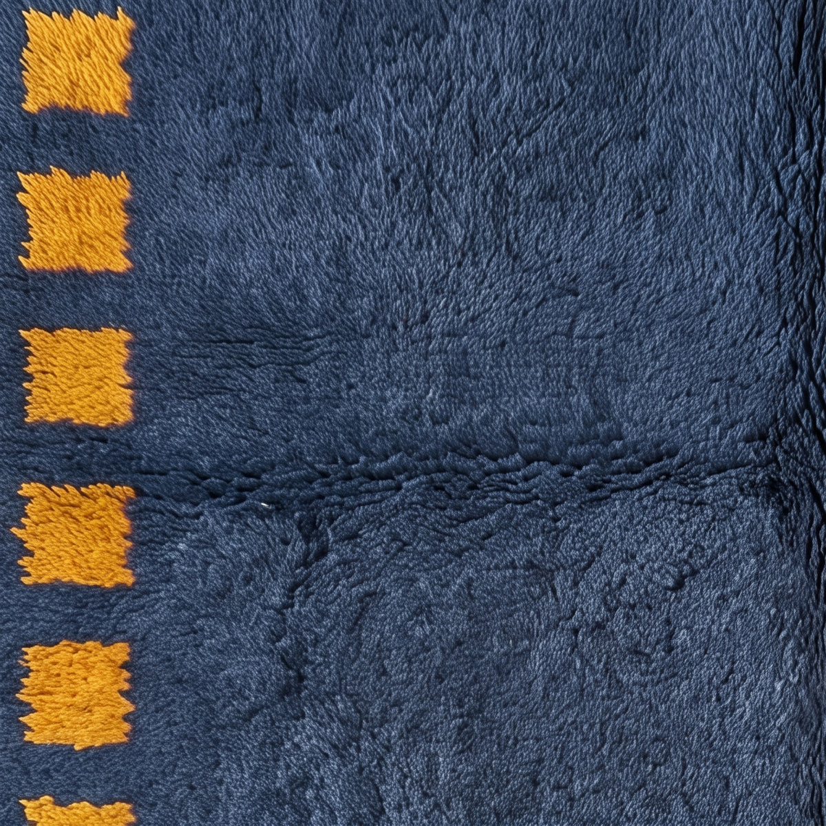 Angled pile detail showing texture depth and saffron square motif definition on navy ground