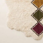Edge and fringe detail of Tafrara showing wavy irregular border, ivory pile, and bottom diamonds in olive, burgundy and gold