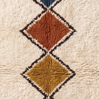 Close-up of terracotta and gold diamond lozenges in Tafrara showing plush wool pile and brown outline detail
