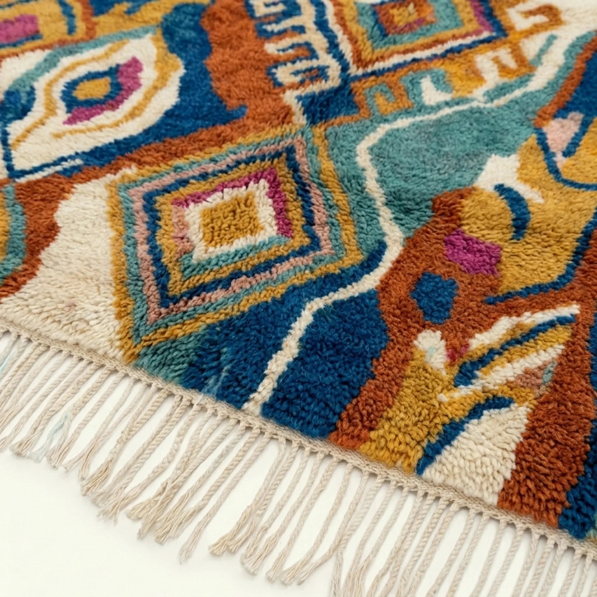 Close-up of the Azwawen Boujaad rug showing nested diamond motifs in navy, teal, terracotta and cream