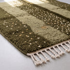 Corner detail of Mrirt rug showing dense dots on dark olive ground and fawn solid band with fringe edge