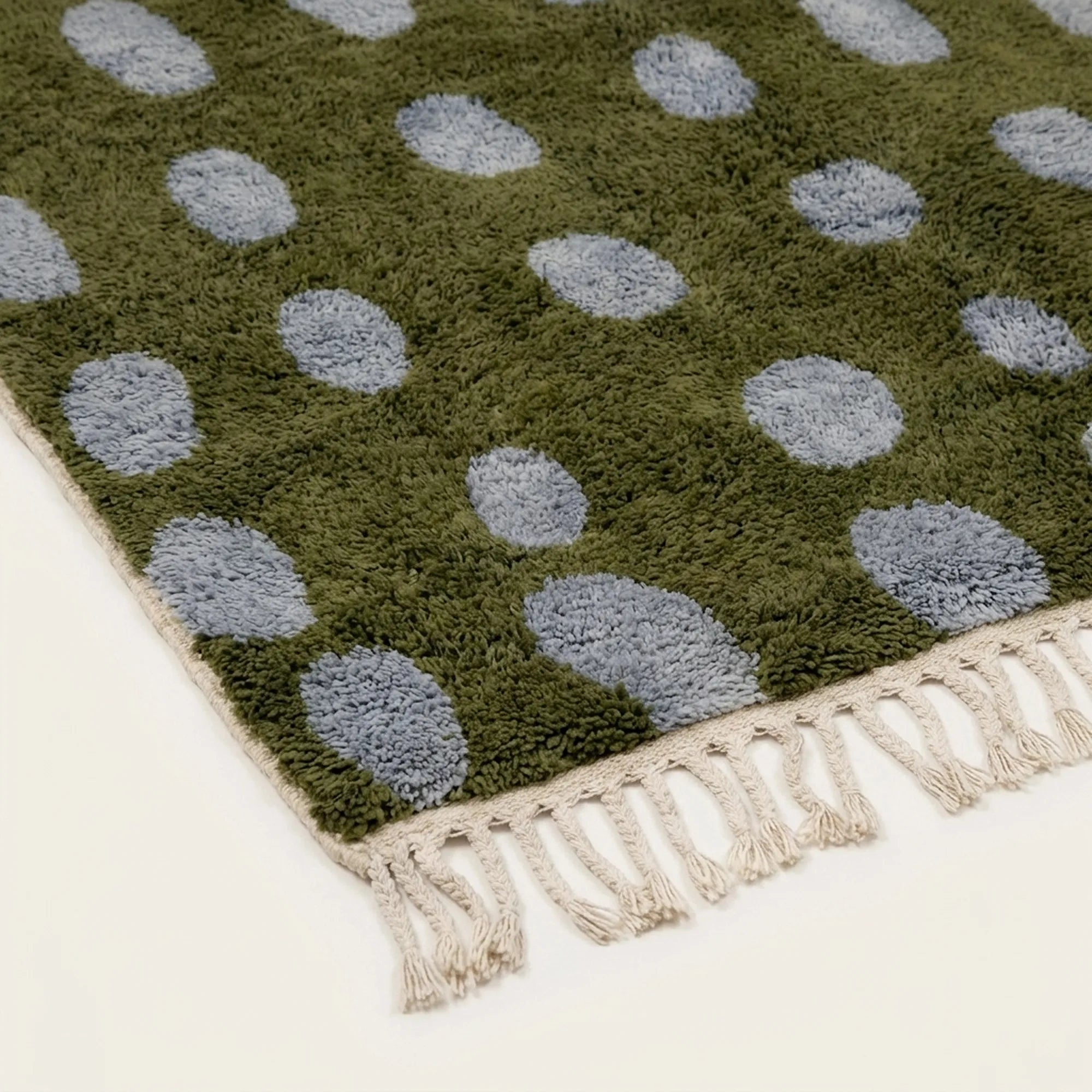 Angled view of the Azil olive green and slate blue Beni Ourain rug showing the oval grid design.