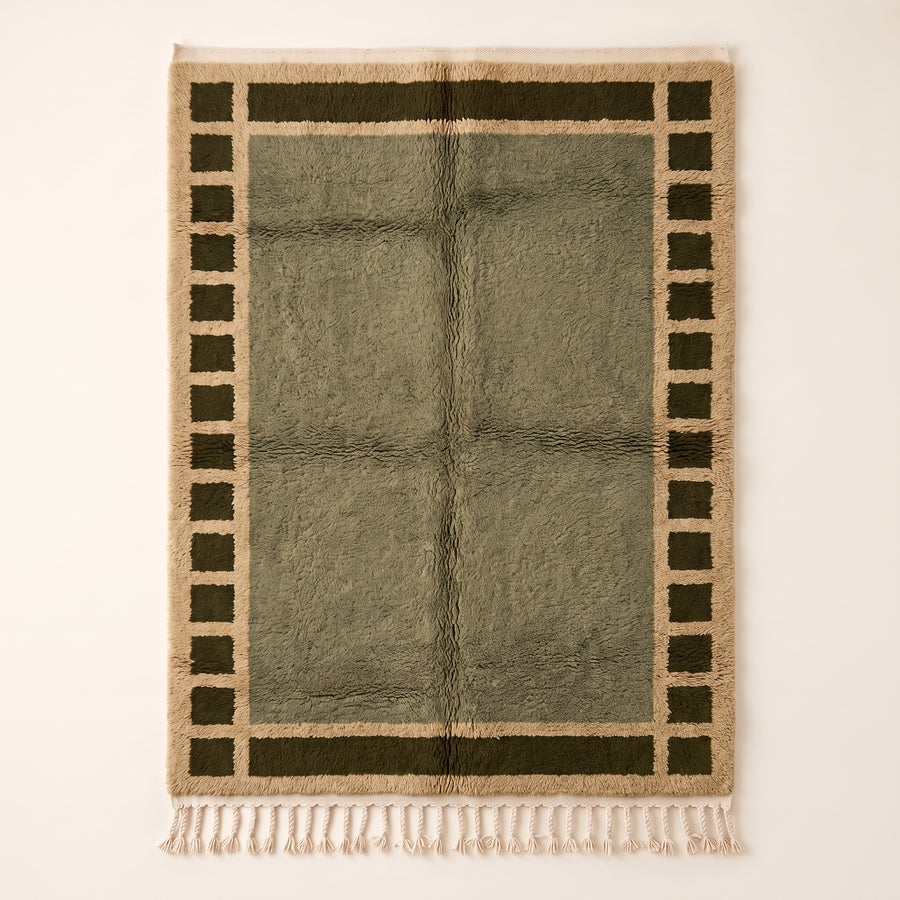 Olive and ivory Mrirt rug with checkered border frame design on plain background
