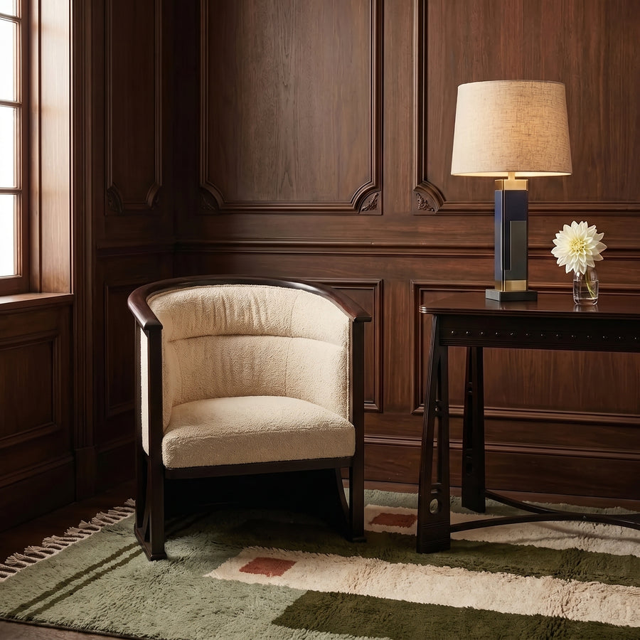 Olive and ivory Mrirt rug layered in modern study with dark wood panelling, cream armchair and desk