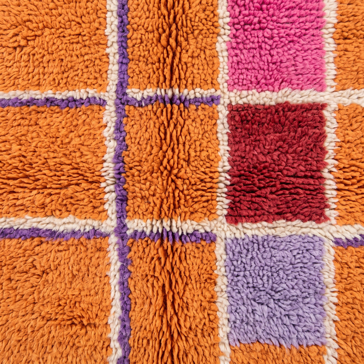 Corner detail of the orange Mrirt grid rug showing cream twisted fringe edge and the meeting of coloured blocks