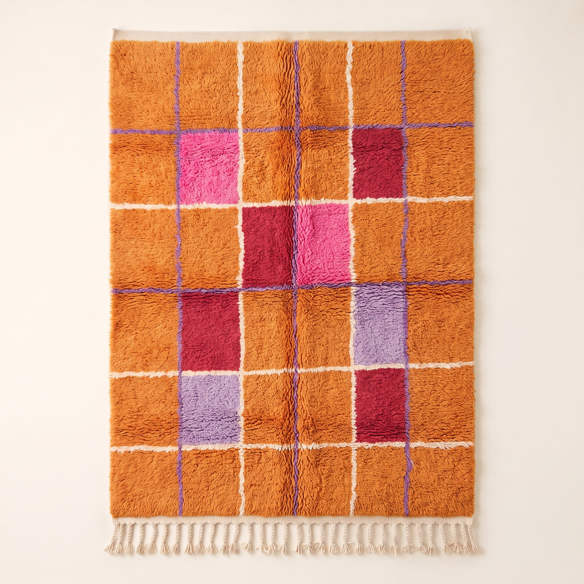 Orange, hot pink, deep red and purple Mrirt rug with geometric window grid pattern separated by white and periwinkle lines, flat view on plain background with cream fringe
