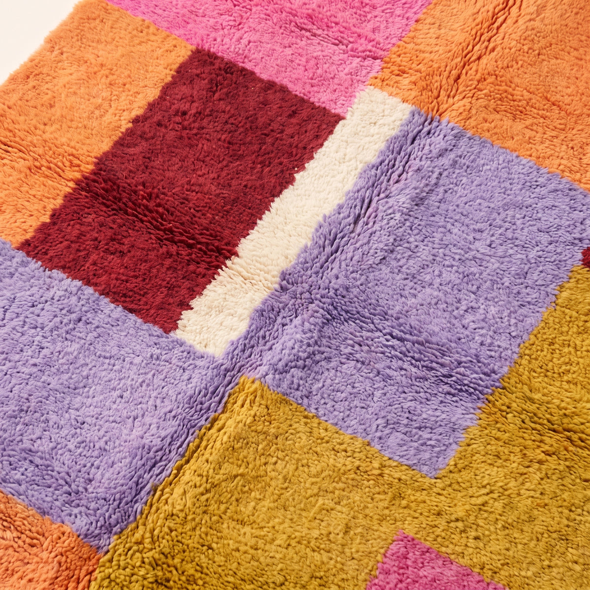 Close angled view of Zayna Azilal rug showing pile depth and colour block transitions in pink, orange, lavender and mustard