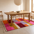 Zayna Azilal rug in dining room under wooden table with chairs, bright colour blocks adding warmth to minimalist space