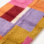 Close-up detail of Zayna Azilal rug pile, showing dense plush weave and colour transitions between pink, burgundy, lavender and gold
