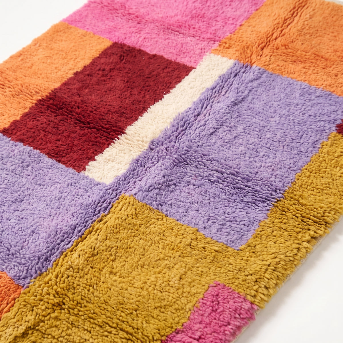 Close-up detail of Zayna Azilal rug pile, showing dense plush weave and colour transitions between pink, burgundy, lavender and gold