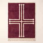 Plum and ivory Beni Ourain rug with bold geometric cross motif and decorative terminals, flat lay on plain background