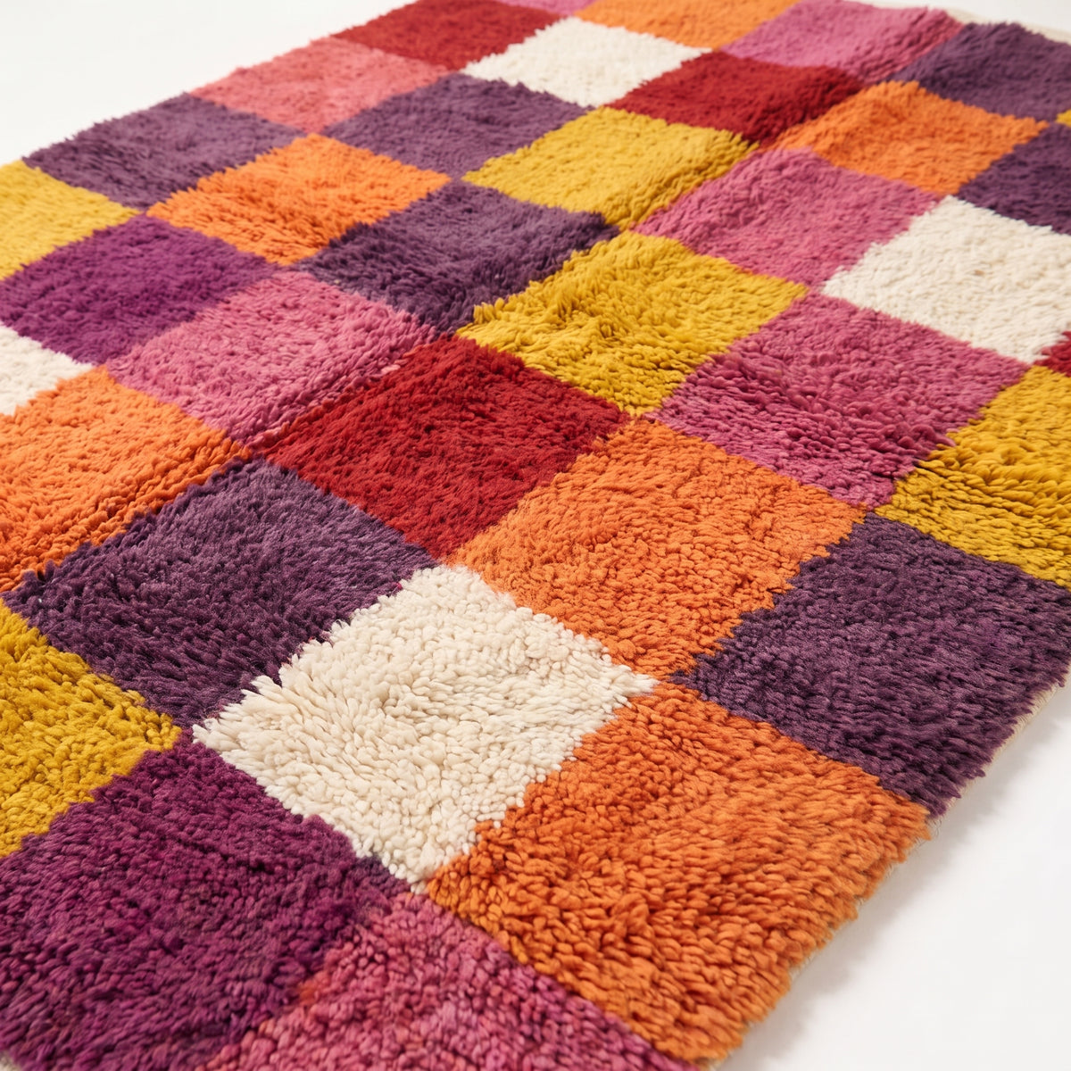 Close-up detail of dense hand-knotted wool pile showing colour transitions between red, orange, purple and gold squares